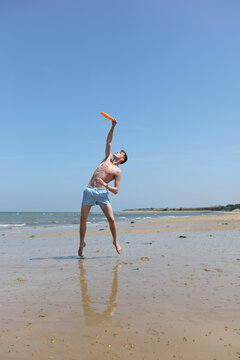 Young man playing frisbee on the beach