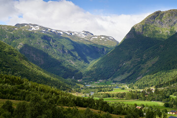Naklejka na ściany i meble Small farms with green fields amongst the Norwegian high mountains, close to Hemsedal