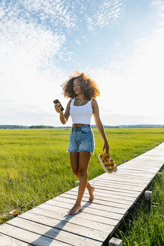 Young African American Teen Girl With Cell Phone walking to Beach