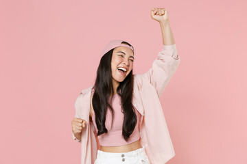 Joyful young asian woman girl in casual clothes cap posing isolated on pastel pink wall background...