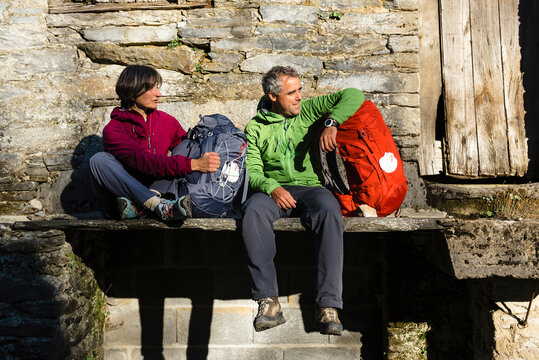 Couple of pilgrims having a break seated on a stone floor of rural house