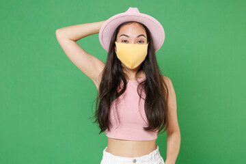 Young asian woman girl in casual pink clothes hat yellow face mask isolated on green wall...