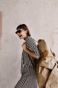 Laughing artistic woman carrying abstract baggage