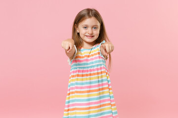Little female kid girl 5-6 years old in colorful dress blue eyes pointing fingers camera isolated on pink background children studio portrait. People childhood lifestyle concept. Mock up copy space