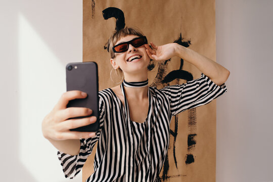 Joyful creative woman in sunglasses taking selfie