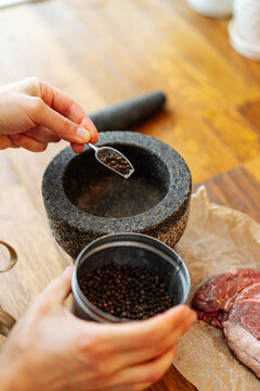 Cook measuring pepper peas for grinding in mortar