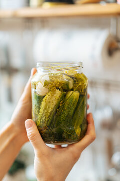 Glass bottle with pickles in hands