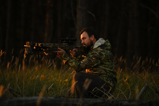 Adult man hunting with a recurved crossbow in the forest on an autumn day.