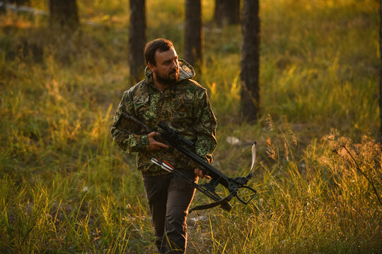 Adult man hunting with a recurved crossbow in the forest on an autumn day.