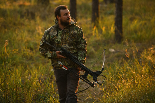 Adult man hunting with a recurved crossbow in the forest on an autumn day.
