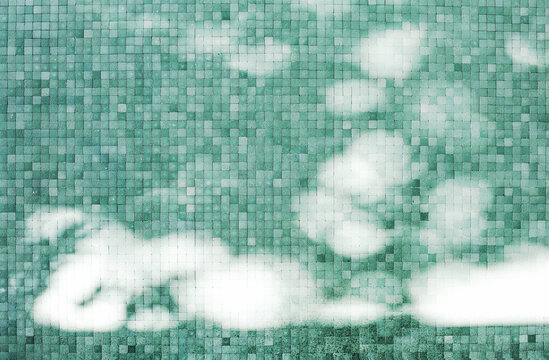 Sunrays glistering on teal and green mosaic wall in MIlan streets