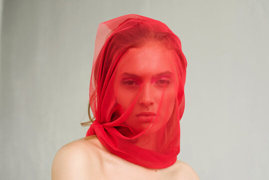 Beauty portrait of a girl covered by red veil
