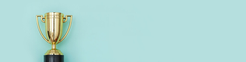 Simply flat lay design winner or champion gold trophy cup isolated on blue pastel colorful...