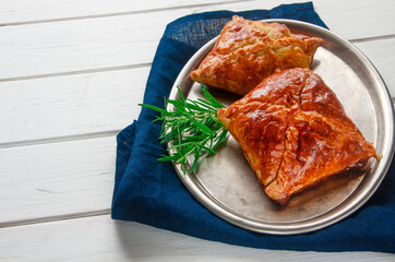 Homemade pastries with meat and spicy sauce with rosemary served on a metal tray on white wooden table