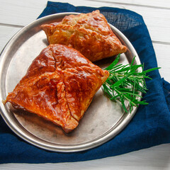 Homemade pastries with meat and spicy sauce with rosemary served on a metal tray on white wooden table