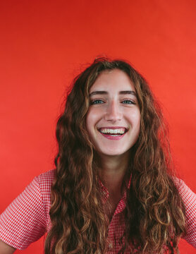 Portrait of smiling teenage girl in front of red backdrop