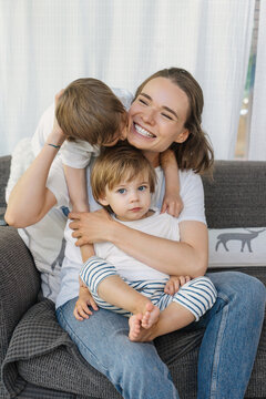 Happy mother cuddling with kids on sofa
