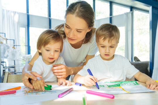 Children drawing together with mother at home
