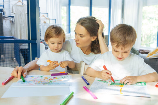 Children drawing together with mother at home