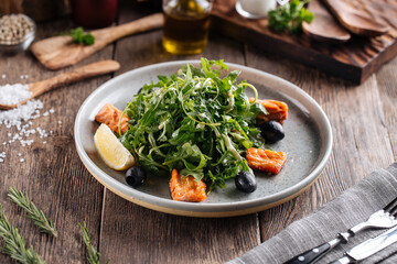 Fresh arugula salad with salmon and olives