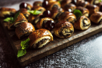 buns with poppy seeds with cherries, mint leaves on a brown wooden board on a gray background 5