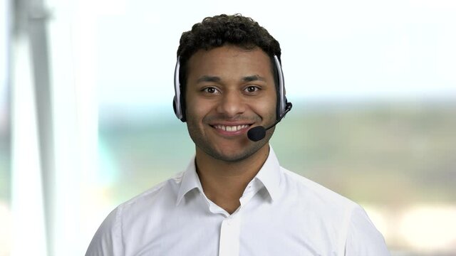 Male technical support operator in headset. Customer service worker talking to camera on blurred background. Call center operator at work.