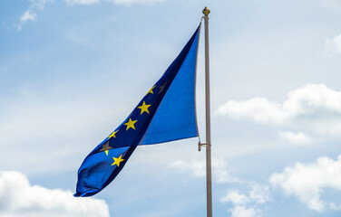 European Union flag on a flagpole against the sky with clouds