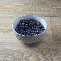 blueberries in a grey bowl on a wooden table