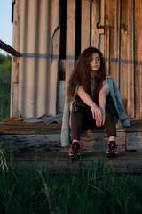 Young girl in denim clothes sits on an old wooden terrace