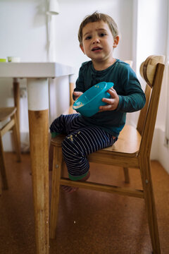 Disappointed Child Carelessly Holding Bowl With Porridge