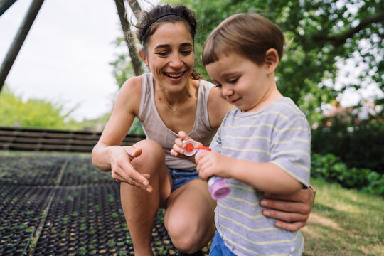 Mother blowing bubbles with son in backyard