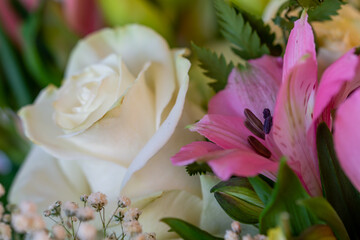 Close-up view of a bouquet of fresh varied flowers with multi-colored roses, buds, ferns, lisianthus