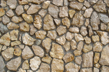 The wall is made of various stones held together with cement.