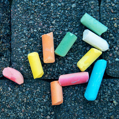 Blurred image Colorful pastel sidewalk chalk on dark asphalt background. children's crayons on the asphalt close up. The concept of development of children's creativity. selective focus. No focus