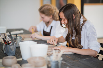 Obraz na płótnie Canvas Beautiful young female artist girls creating handmade pottery in modern art studio. Education kids and parents.