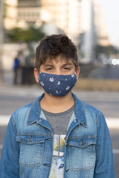 Retrato de menino andando pelas ruas da cidade usando m&aacute;scara de prote&ccedil;&atilde;o durante a pandemia e flexibiliza&ccedil;&atilde;o da quarentena. 