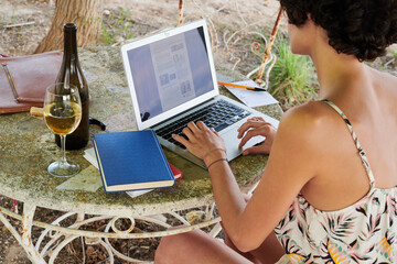 Girl in light dress using laptop in garden