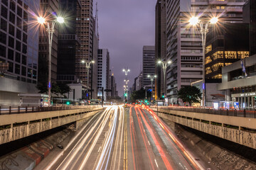 Fototapeta na wymiar Imagem em longa exposição noturna da Avenida Paulista com rastro das luzes dos veículos 