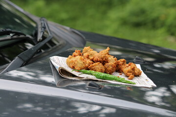 Crispy moong pakora, delicious street food, favourite indian snack in monsoon served with Hot Tea.Kept on car's bonnet