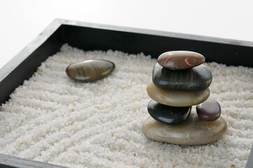 Stacked polished rocks in a miniature Zen rock garden sandbox
