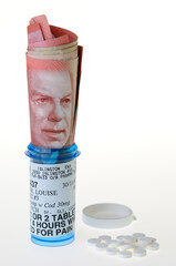 50 dollar Canadian bill in a prescription bottle for pain with pills on a white background