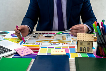 Interior designer's hand working with illustration sketch, color scheme of material, notebook and...
