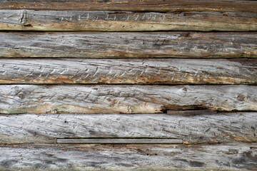 Vintage rustic background. House wall in the village. Large, untreated gray logs in a horizontal arrangement.