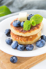 A healthy breakfast of pancakes, berries, butter, and honey.