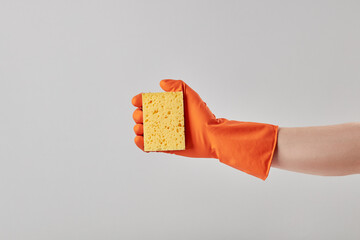 caucasian male person wearing orange cleaning glove and holding yellow washing sponge. isolated over grey background. studio shot. copy space.cleaning service concept.