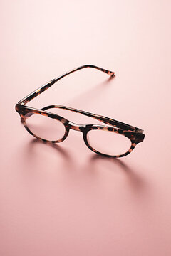 Backlit tortoise shell retro style reading glasses on a pink background
