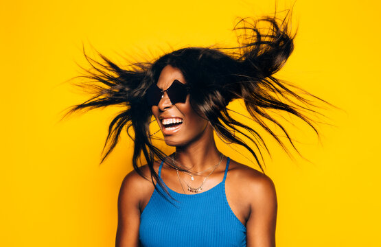 Happy Afro Woman posing over yellow background moving her hair