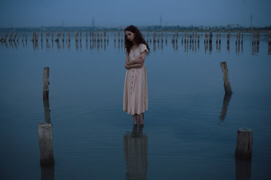 girl in a dress stands in the water in the evening