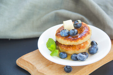 A healthy breakfast of pancakes, berries, butter, and honey.