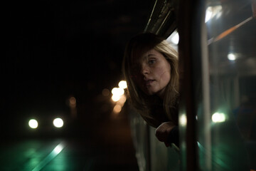 girl peeks out of a transport window at night